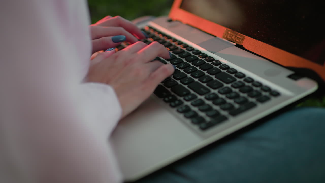 primer plano de una mujer escribiendo en una computadora portátil con uñas bien pulidas, luz solar reflejada en el teclado, efecto de luz bokeh suave en el fondo