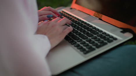 close-up of woman typing on laptop with well-polished nails, sunlight reflecting on the keyboard, soft bokeh light effect in the background