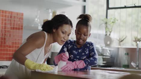 Happy-african-american-mother-and-daughter-cleaning-kitchen-together,-slow-motion