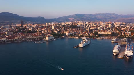 Enthüllung-Der-Drohne-Während-Des-Sonnenuntergangs-Von-Split-In-Kroatien-Mit-Stadt-Und-Meer-Im-Vordergrund-Und-Bergen-Im-Hintergrund-In-4k,-Die-Rückwärts-Fliegen