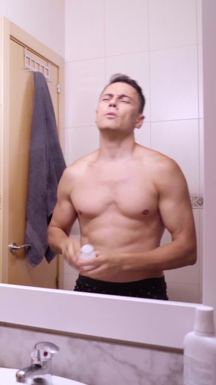 Man applying deodorant in bathroom mirror