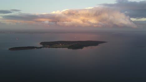 Una-Grabación-De-Un-Dron-Distante-De-Una-Isla-Al-Atardecer-Con-Couds-Coloridos-Encima