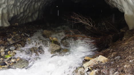 Melt-water-coming-out-of-a-tunnel-under-the-ice-after-an-avalanche-in-winter