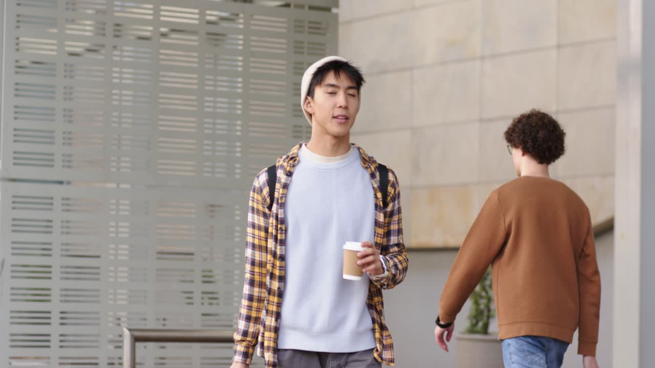 Starting morning commute through urban walkway, Asian man pulling suitcase and sipping coffee