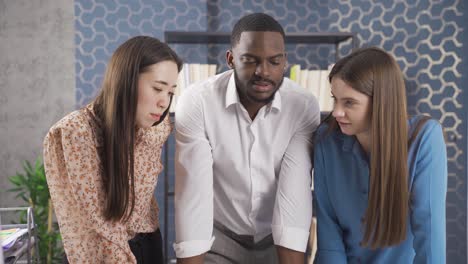 multiethnic young asian woman black man and european woman working in office and discussing on computer and project.