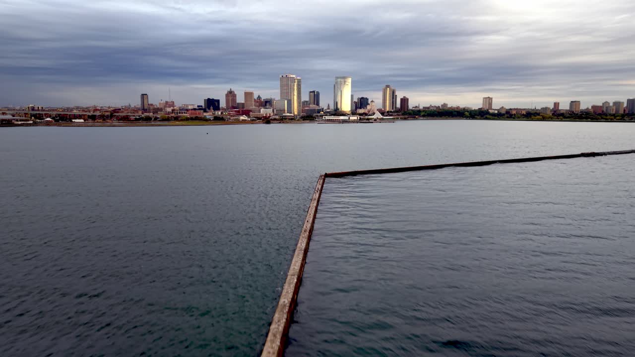 aerial push in over the Milwaukee Breakwater Light Lighthouse with Milwaukee skyline in the distance
