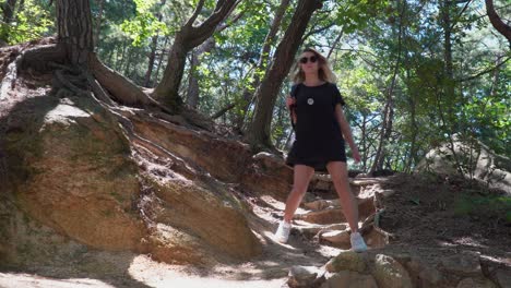 Weibliche-Wanderer-Rucksacktouristin-In-Schwarzer-Kleidung,-Die-An-Einem-Sonnigen-Sommertag-Den-Felsigen-Hanghügel-Im-Gwanaksan-bergwald-In-Südkorea-Hinuntergeht---Aus-Dem-Niedrigen-Winkel