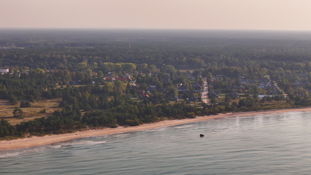 라트비아의 파빌로스타의 공중 풍경, 모래 해변과 평화로운 마을이 있습니다.