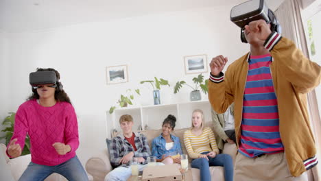 happy diverse group of teenage friends with pizza playing with vr headsets at home, slow motion