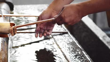 Slide-shot-of-a-person-washing-hands-at-a-temple-in-Kyoto,-Japan-4K