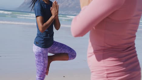 multi-ethnic group of women doing yoga position on the beach and blue sky background
