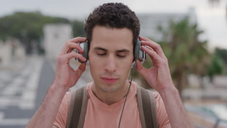 retrato joven hispano guapo se pone auriculares disfrutando escuchando música en unas vacaciones de verano relajadas estudiante despreocupado en cámara lenta