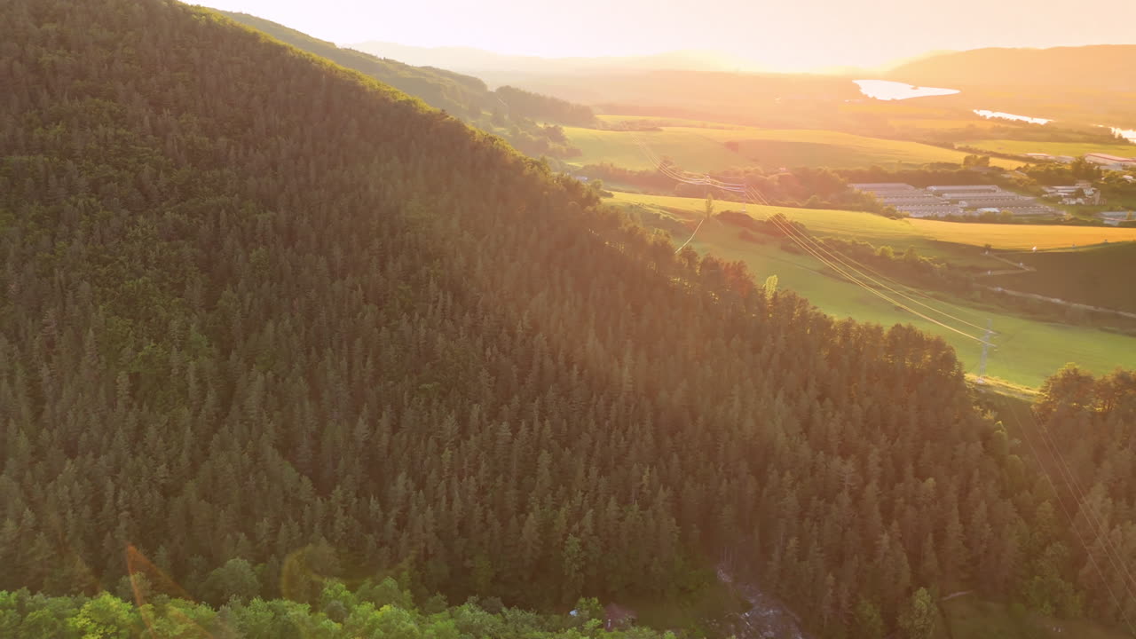 Sunlight bathes lush forested mountain. Rays of sunlight touch the green forest on a mountain, showcasing the serene landscape at sunset