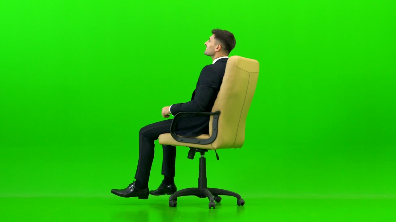 행복 한 사업가 는 초록색 배경 에 있는 사무실 의자 를 켜고 있다