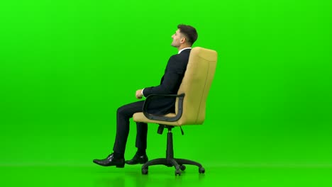 the happy businessman turning on the office chair on the green background