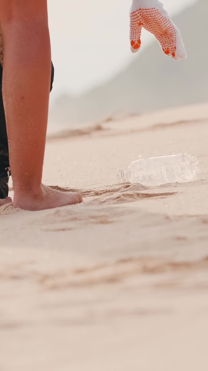 Person removes plastic bottles from beach throwing waste into bag