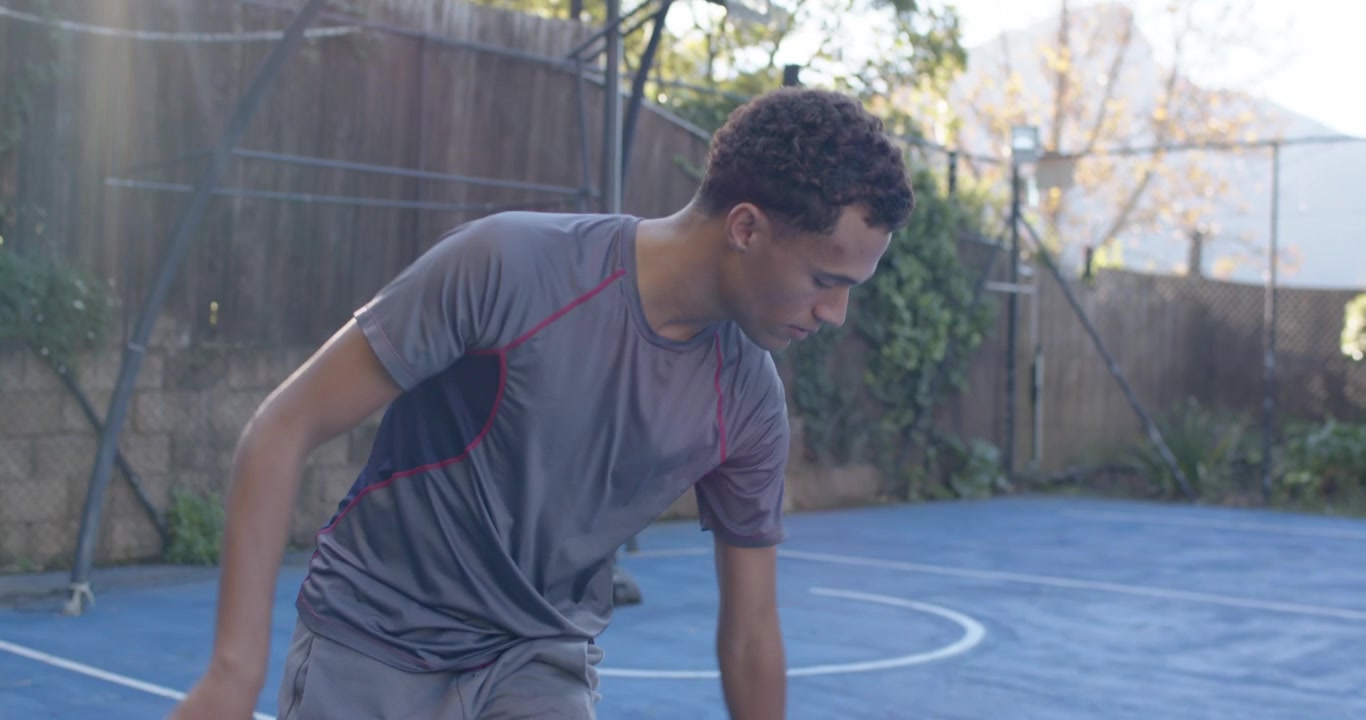 African American man starting practice, dribbling crossover on blue court with hoop and basketball