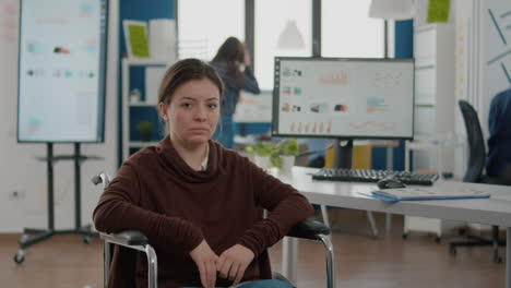 Young invalid woman entrepreneur sitting on wheelchair looking at camera