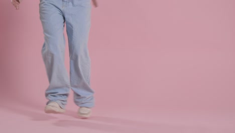 close up on legs and feet of woman having fun dancing against pink studio background 1