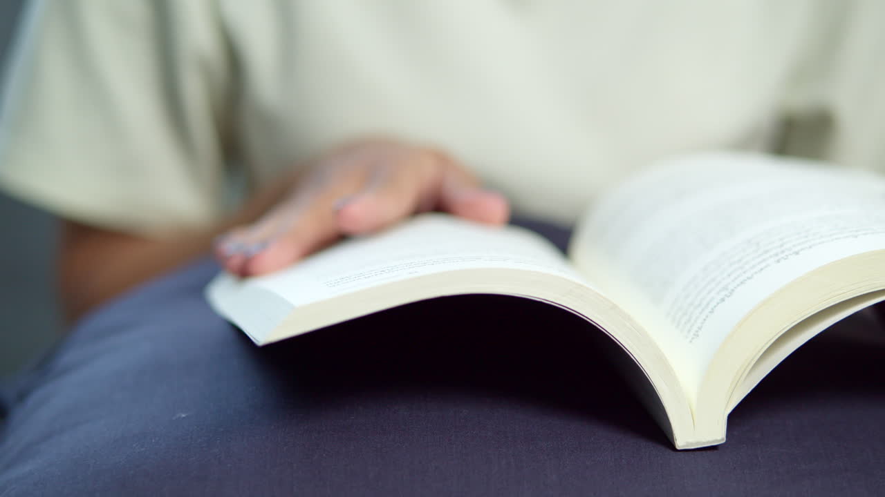 A person enjoying a quiet moment flipping through pages of a book in a serene indoor setting