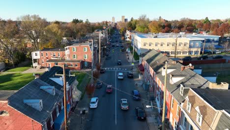 one way street lined with row houses headed towards american city during autumn