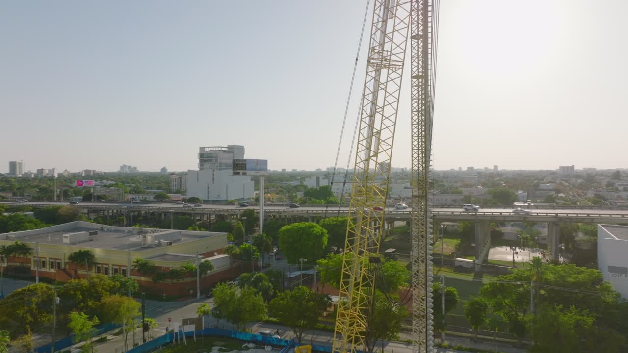 orbita tomada alrededor de maquinaria de construcción. carretera elevada y concurrida en el fondo. vista contra el sol. miami, ee.