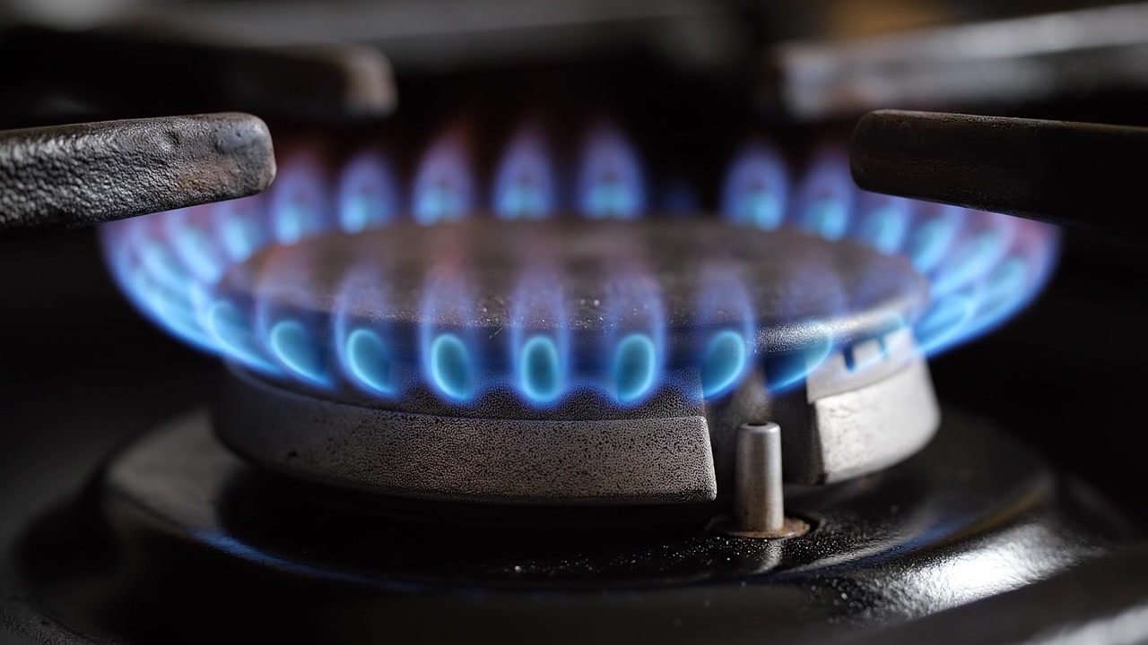 Close up of blue flame burning on gas stove burner