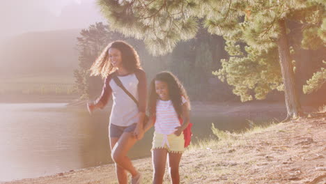 family on hike walking along path through woods next to lake