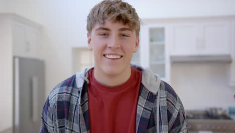 portrait of happy caucasian male teenager with blond hair at home, slow motion