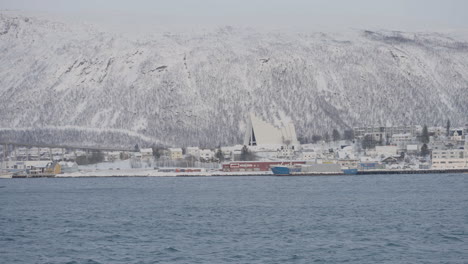 astonishing view of rocky mountains covered in snow at the embankment of tromsoysundet strait in tromso, norway during winter