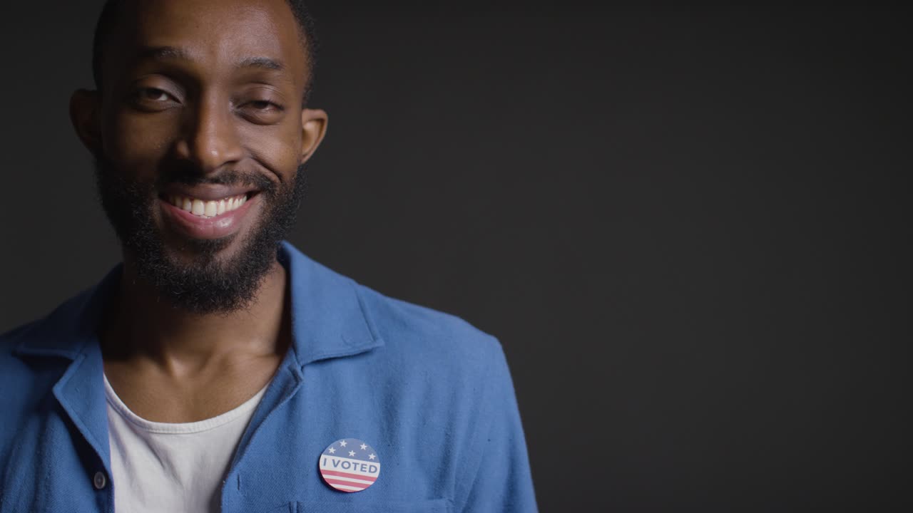 Portrait Of Man Putting I Voted Sticker On Shirt In American Election