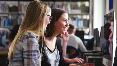 dos estudiantes mujeres trabajando en la computadora en la biblioteca de la universidad