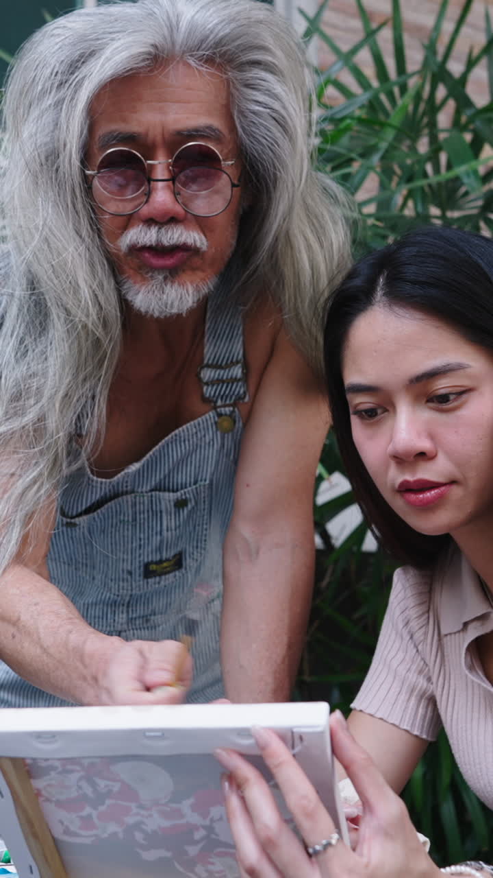 Senior Artist Teaching Young Woman How to Paint Outdoors