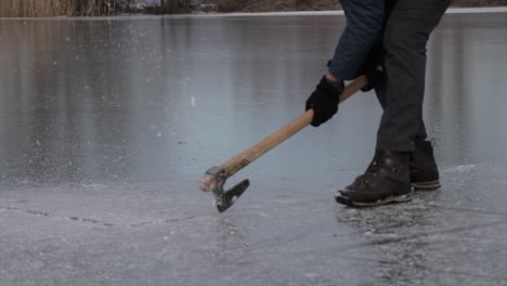 person breaking ice of a frozen lake in winter