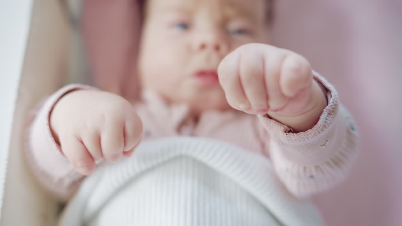 Close up of baby's tiny hand reaching out gently in soft pastel tones