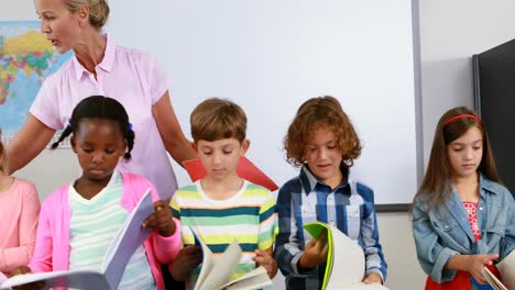 Lehrer-Hilft-Kindern-Beim-Lesen-Von-Büchern-Im-Klassenzimmer