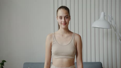 a young woman in a beige top smiles at the camera