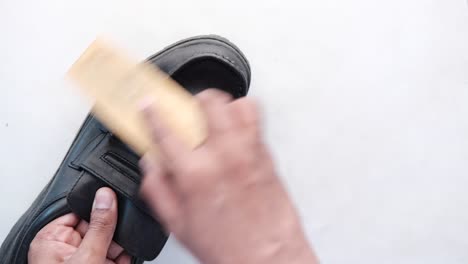 cleaning a black leather shoe with a shoe brush