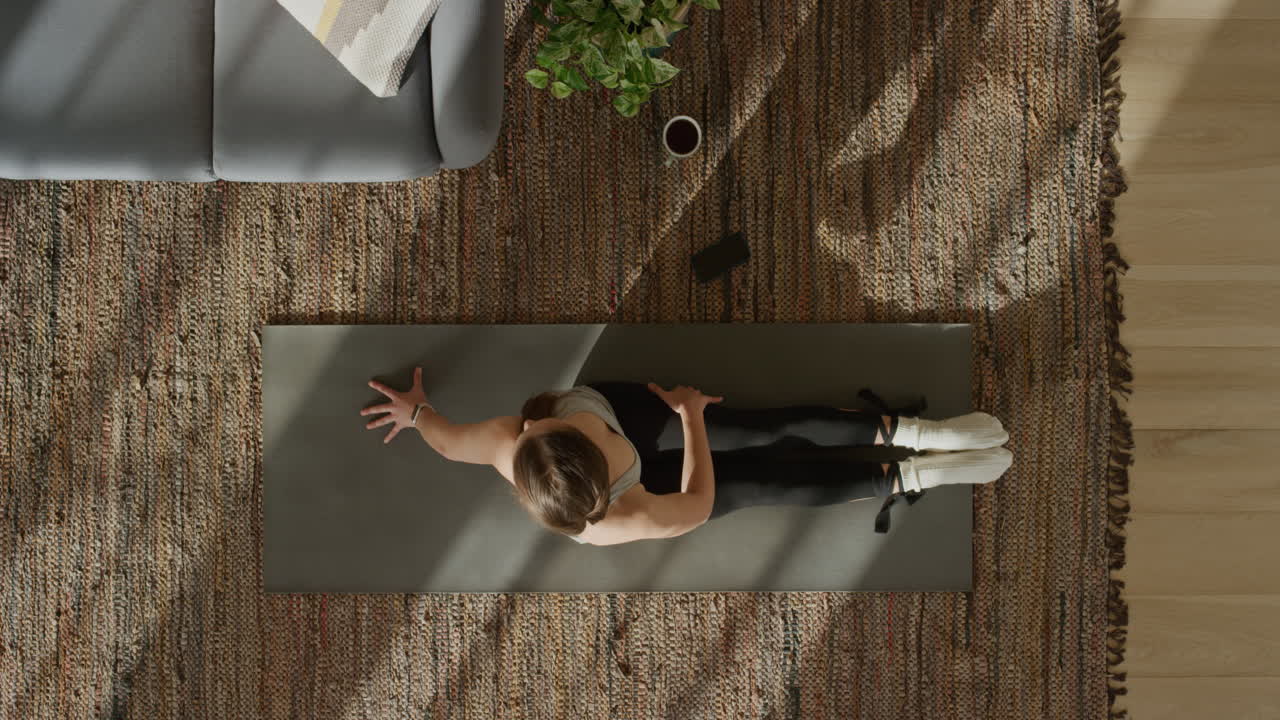 vista superior mujer de yoga ejercitando un estilo de vida saludable estirando el cuerpo flexible disfrutando del entrenamiento en casa practicando atención plena en la colchoneta de ejercicios