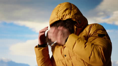 joven viajero luchando con vientos fríos en la cima de la montaña