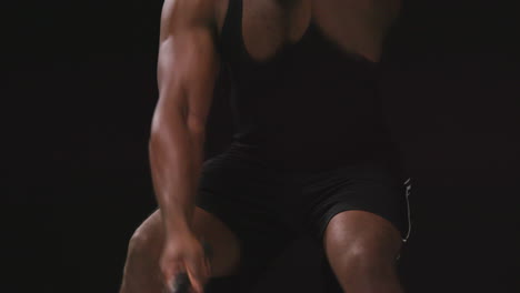 Close-Up-Studio-Shot-Of-Male-Athlete-Training-In-Fitness-Vest-Using-Battle-Ropes-Shot-Against-Black-Background