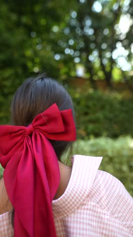 woman with a red bow in a garden