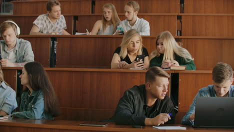 cheerful students are using smartphones and chatting during break between lectures at university. modern technology. cheerful students multiethnic group are