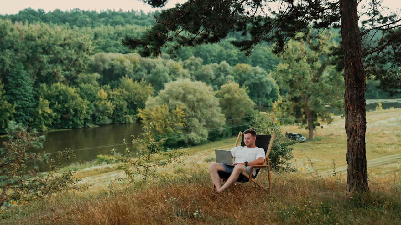 Man sits in a nature working on his laptop. Freelance lifestyle outside the office.