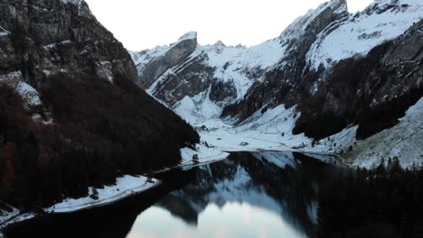 aerial flyover across seealpsee in appenzell, switzerland in winter towards the peaks of alpstein and their reflection - 4k