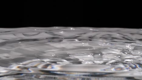 las gotas de agua caen en un líquido transparente ondulante, cierre extremo en cámara lenta