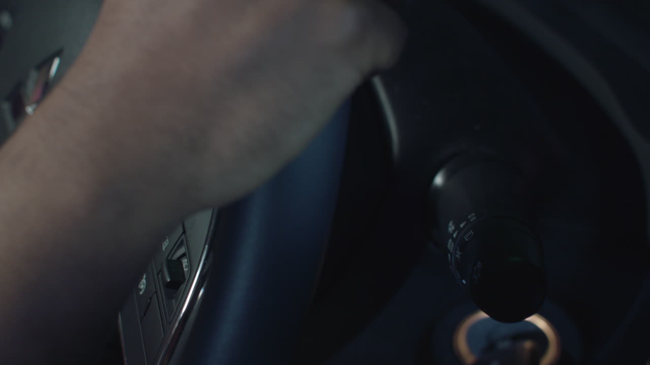 un conductor se baja del volante para encender la señal de giro en un automóvil con interior negro