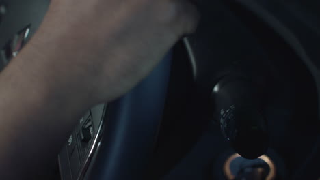 un conductor se baja del volante para encender la señal de giro en un automóvil con interior negro