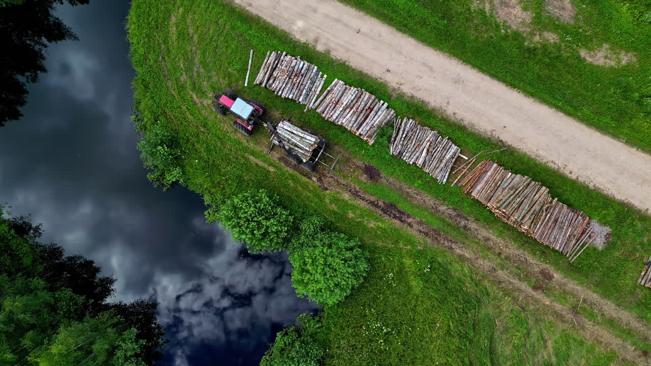 Aerial View of Logging Operation with Tractor and Stacked Logs Next to a River