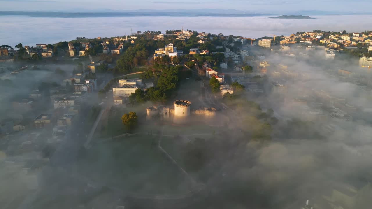Epic view if a church tower protruding through low hanging clouds during sunrise 4k drone shot video. Drone is slowly flying above a church tower that is only partially visible, sunrise, golden hour